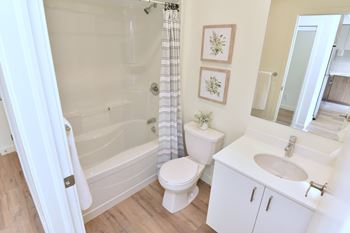 A white bathroom with a toilet, sink, and bathtub